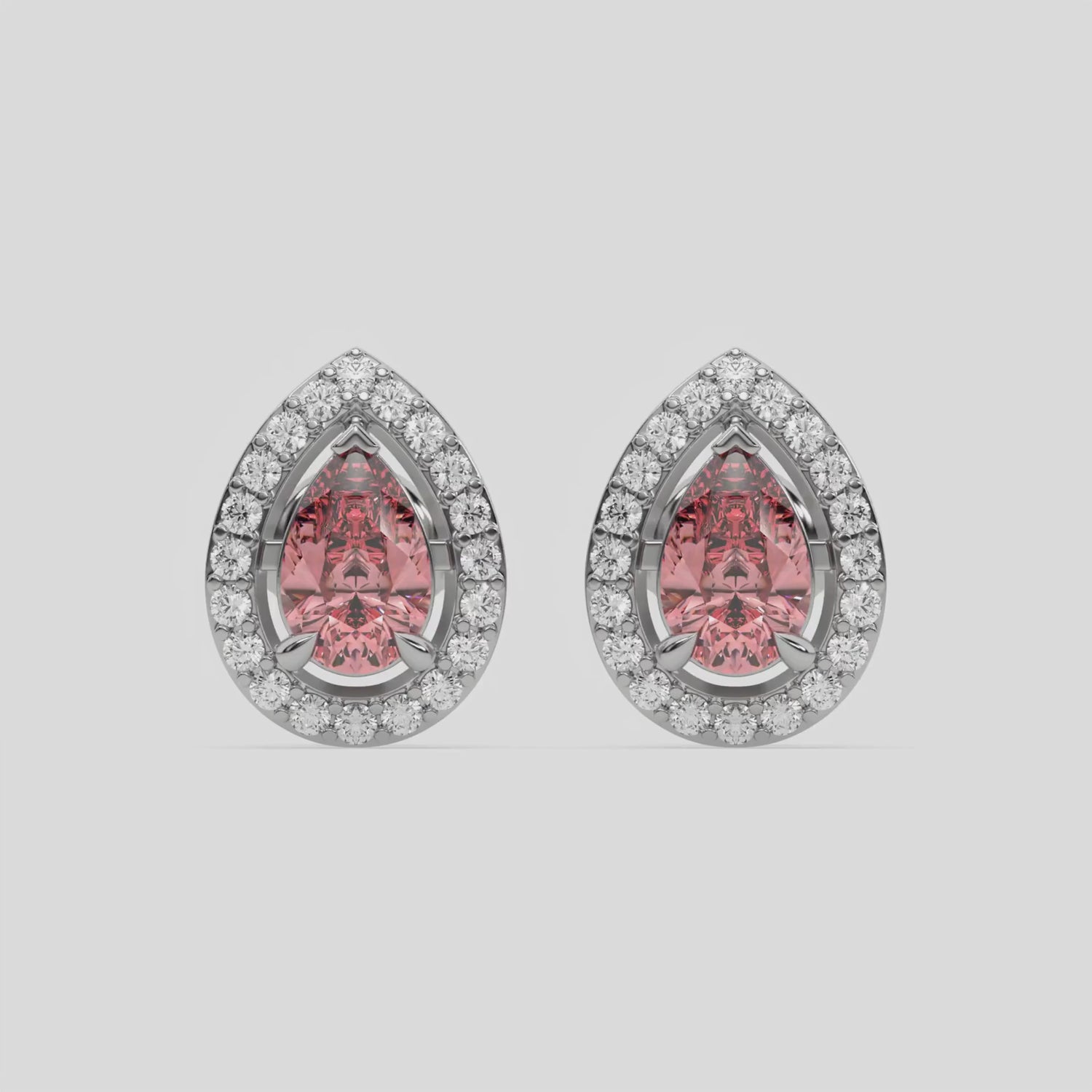 This video features a white gold Classic Pear Diamond Halo Earrings made with a fancy pink pear cut solitaire diamonds set in a four prong setting