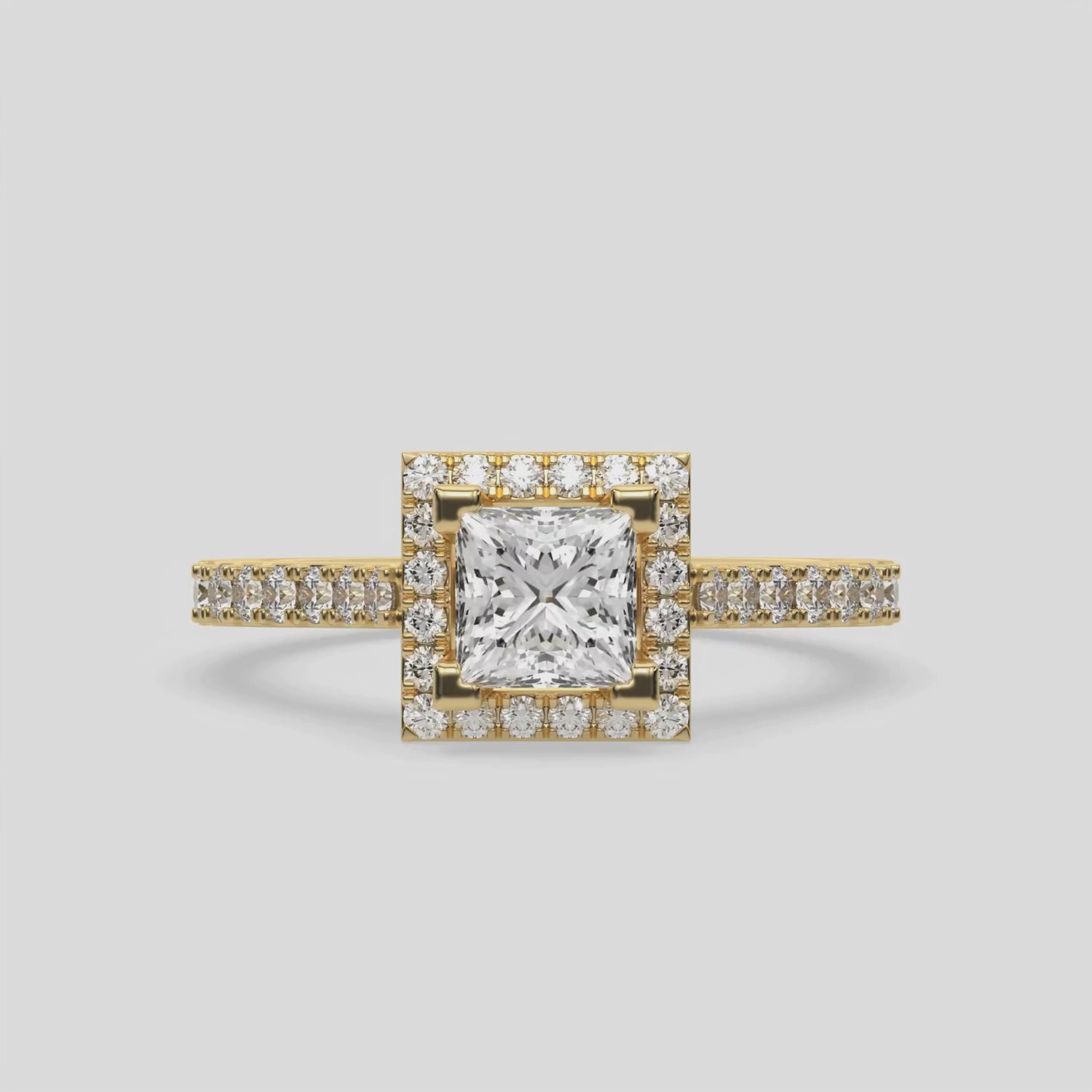 This video features a yellow gold Princess Diamond Halo Engagement Ring is made with a princess solitaire diamond set in a four-prong setting, surrounded by a halo of round diamonds all set on a pave band 