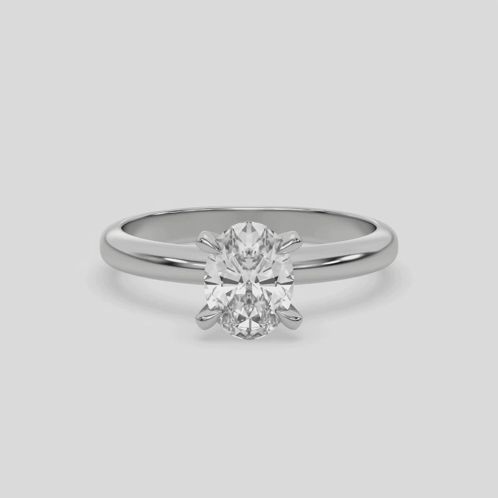 This video features a white gold ring features an oval solitaire diamond elegantly secured in a four-prong setting on a solid gold band 