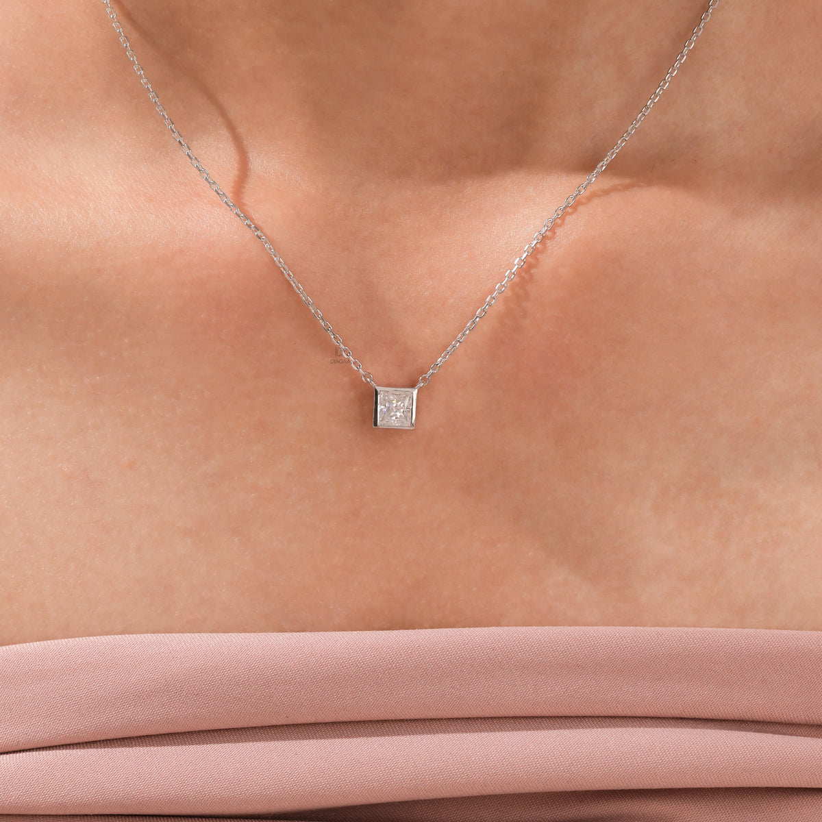 Close-up of an elegant 18K white gold princess Diamond necklace with a square bezel-set diamond on a fine chain.