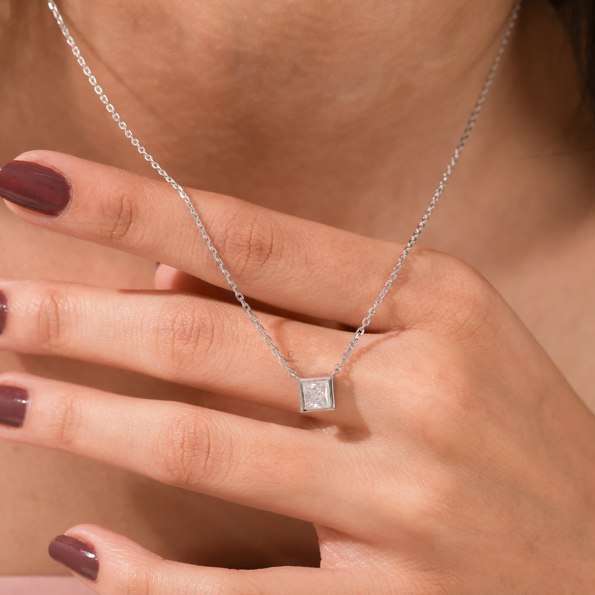 Close-up of an elegant yellow gold princess Diamond necklace with a square bezel-set diamond on a fine chain.