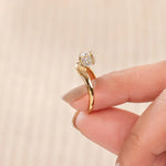 18K yellow gold round diamond solitaire engagement ring with a hidden halo curved band on a woman's hand